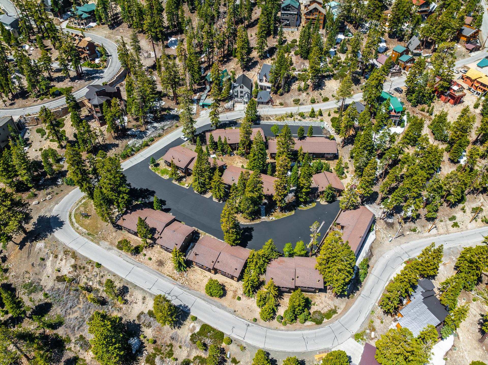 94 John Muir Road, Unit 132 Mammoth Lakes, CA 93546 - Photo 56 of 58 Aerial view of a residential community featuring multiple structures with brown roofs, surrounded by extensive evergreen trees