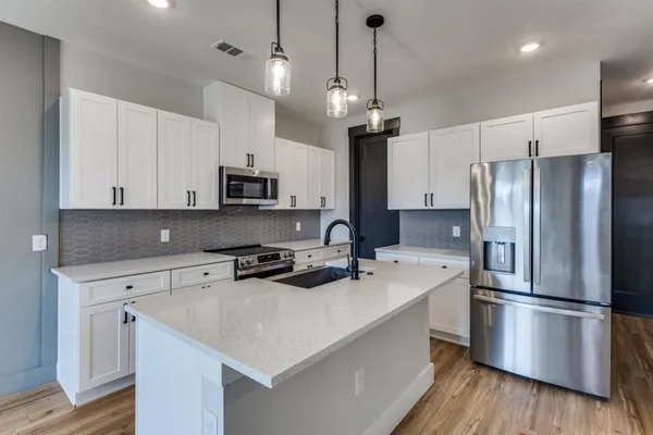 a kitchen with stainless steel appliances a refrigerator a stove a sink and a center island