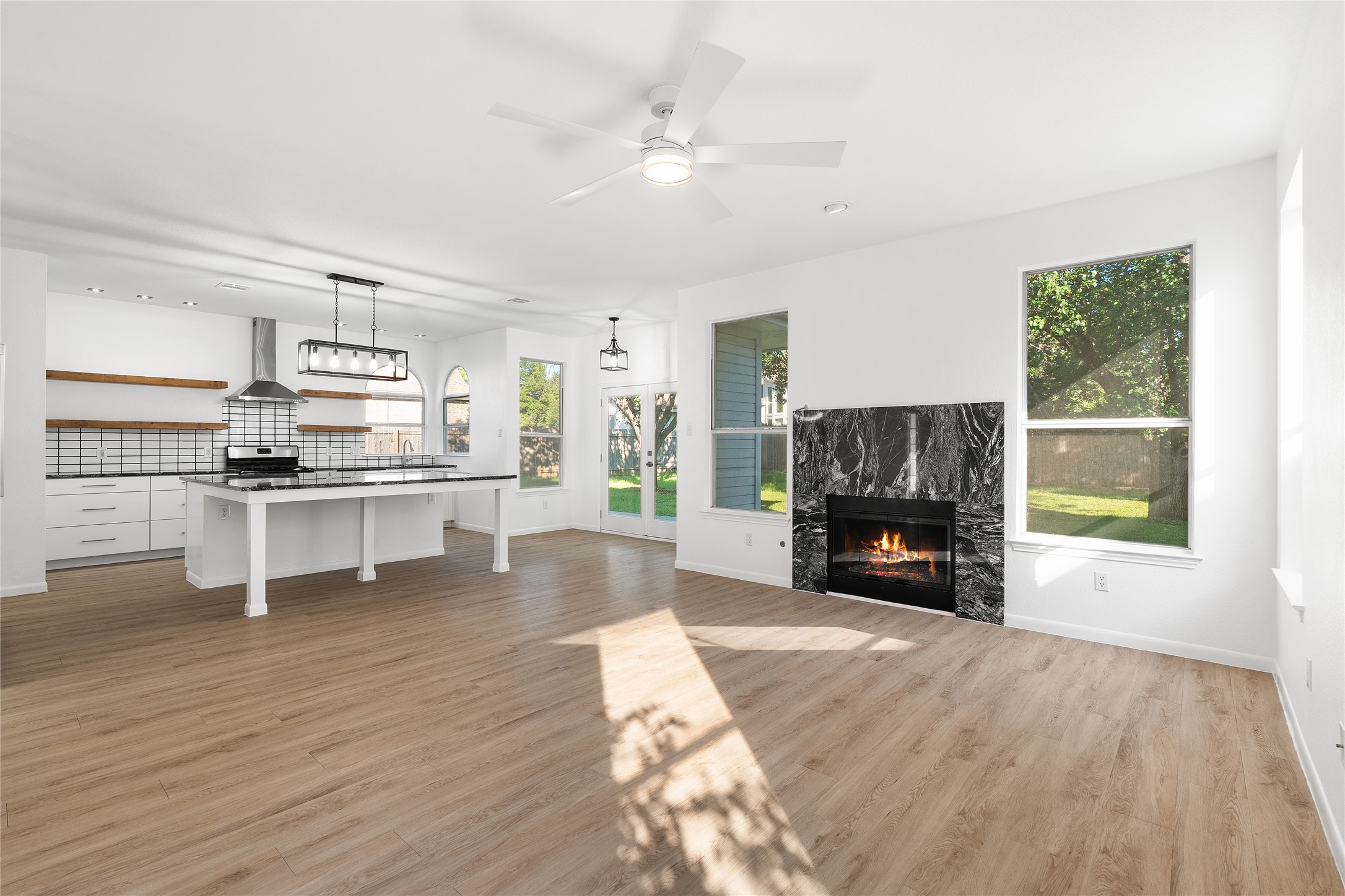 206 River Down Road Georgetown, TX 78628 - Photo 10 of 39 Open-concept interior featuring light wood-finish flooring, a modern fireplace with a dark stone surround, and large windows