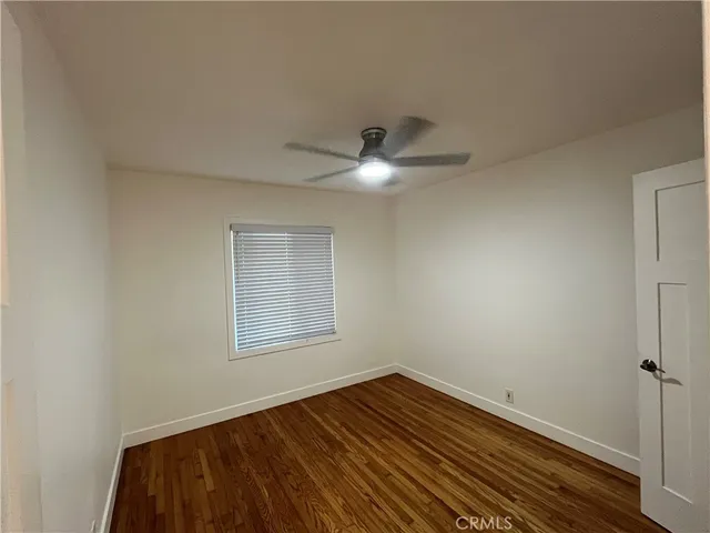 an empty room with wooden floor chandelier fan and windows