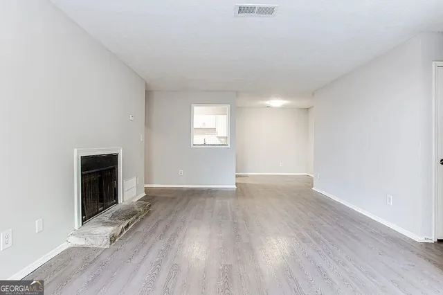 an empty room with wooden floor fireplace and windows
