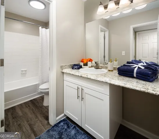 a bathroom with a granite countertop sink a toilet and bathtub