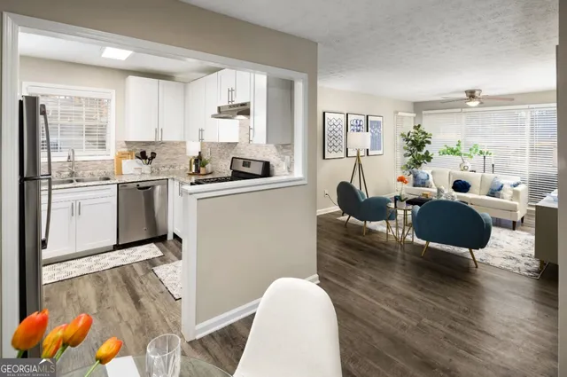 a open kitchen with stainless steel appliances granite countertop a stove top oven a sink dishwasher a dining table and chairs with wooden floor