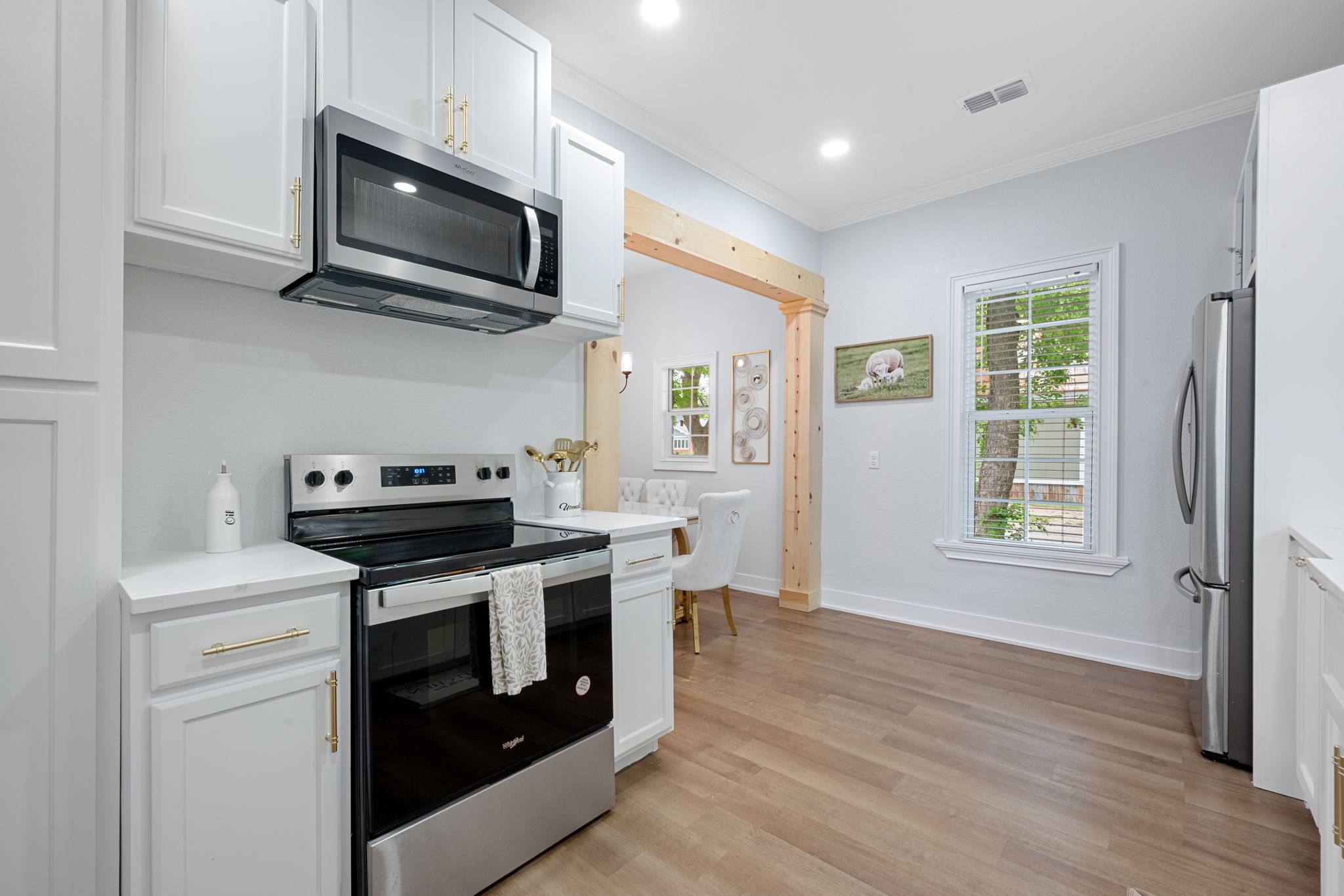 602 East 6th Street Cameron, TX 76520 - Photo 21 of 40 Contemporary kitchen featuring white cabinetry with gold-tone hardware, a stainless steel electric range, and an over-the-range microwave