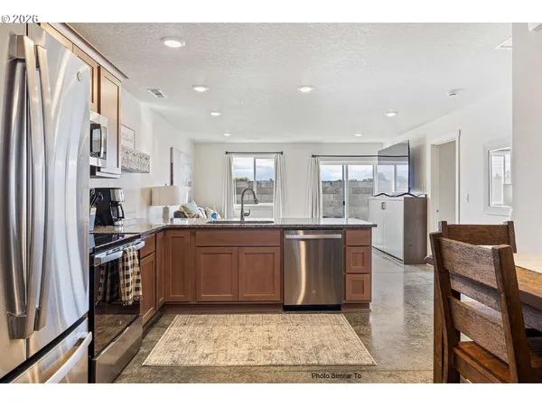 a kitchen with stainless steel appliances granite countertop a refrigerator stove top oven and sink