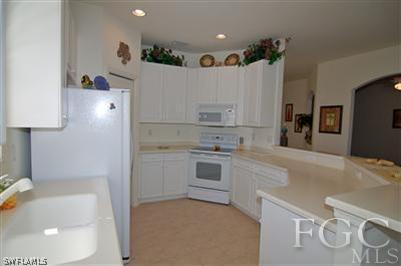 4744 Fairloop Run Lehigh Acres, FL 33973 - Photo 5 of 10 a kitchen with a sink a stove and a refrigerator
