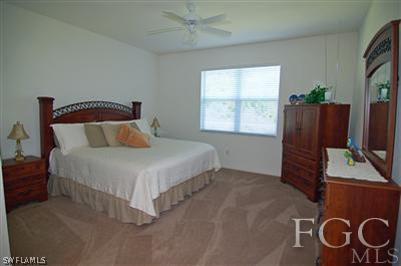 4744 Fairloop Run Lehigh Acres, FL 33973 - Photo 9 of 10 a bedroom with a bed and a flat tv screen on the dresser