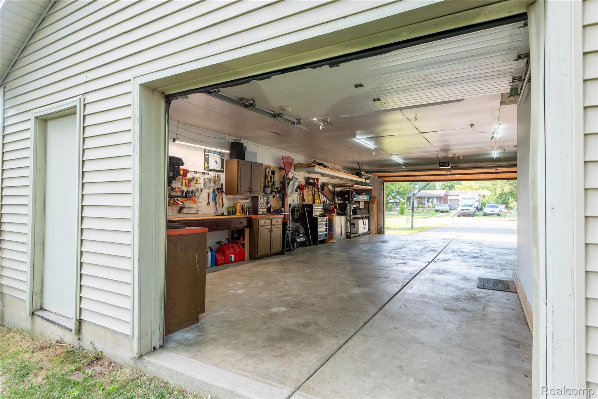4395 Regency Road Swartz Creek, MI 48473 - Photo 10 of 67 Attached garage with concrete flooring, side entry door, built-in cabinetry, and overhead lighting