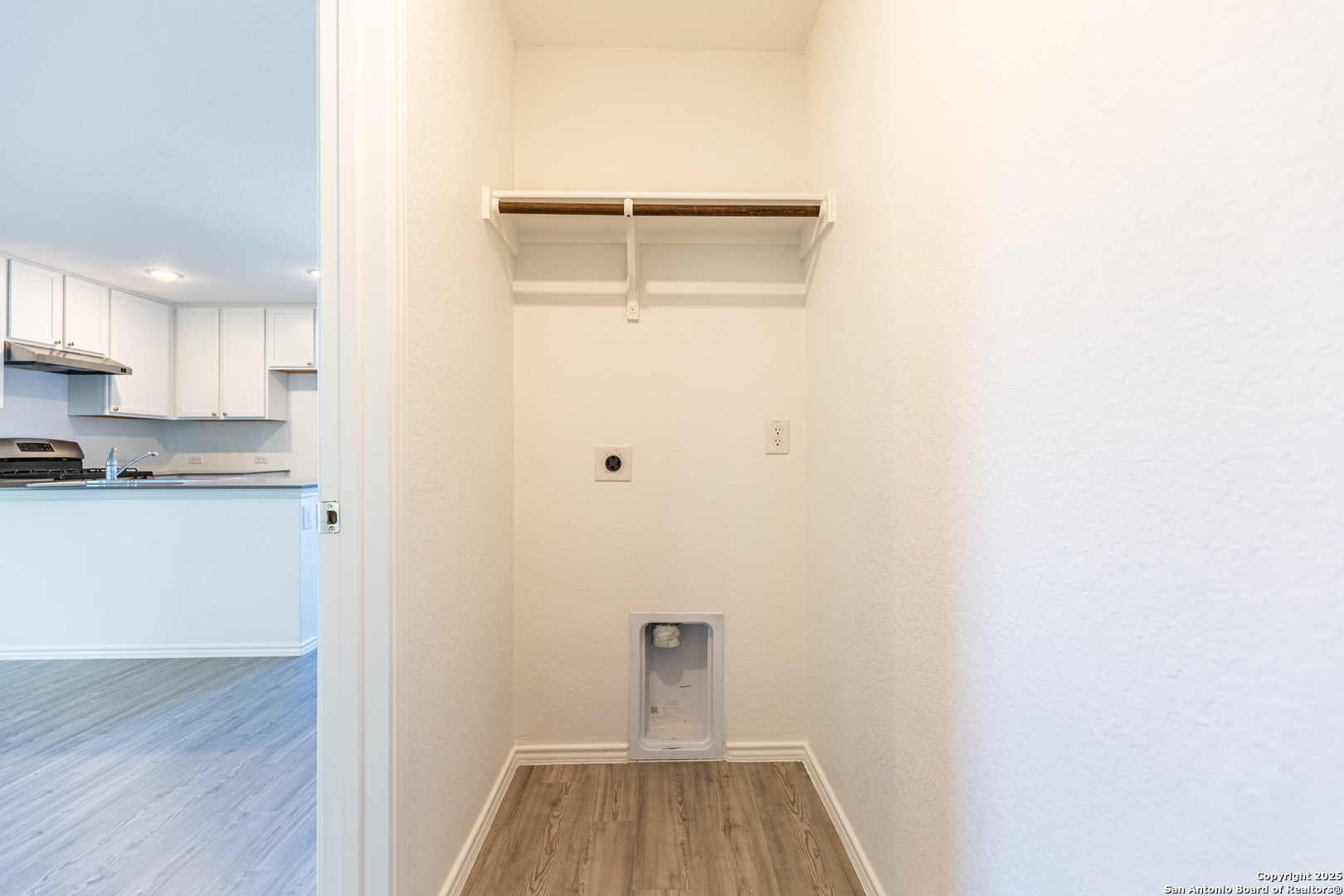 9143 Coronal Rings San Antonio, TX 78252 - Photo 24 of 30 a view of a kitchen with white cabinets and wooden floor