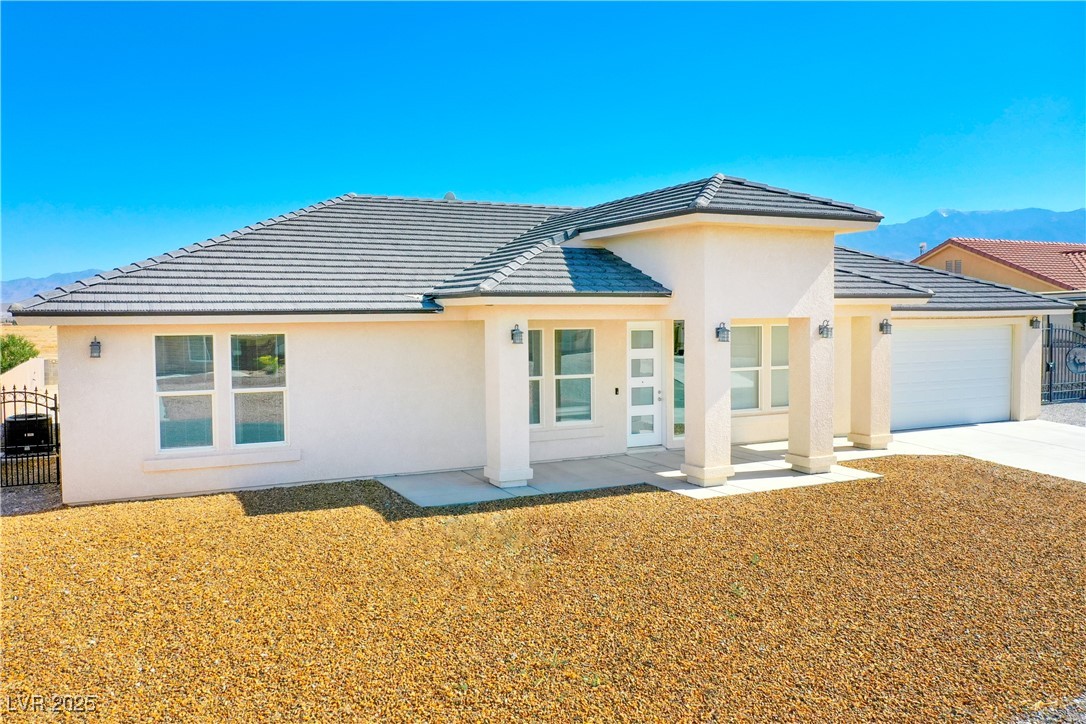 5400 Grain Mill Road Pahrump, NV 89061 - Photo 1 of 67 Rear view of house featuring an attached garage, a mountain view, and stucco siding