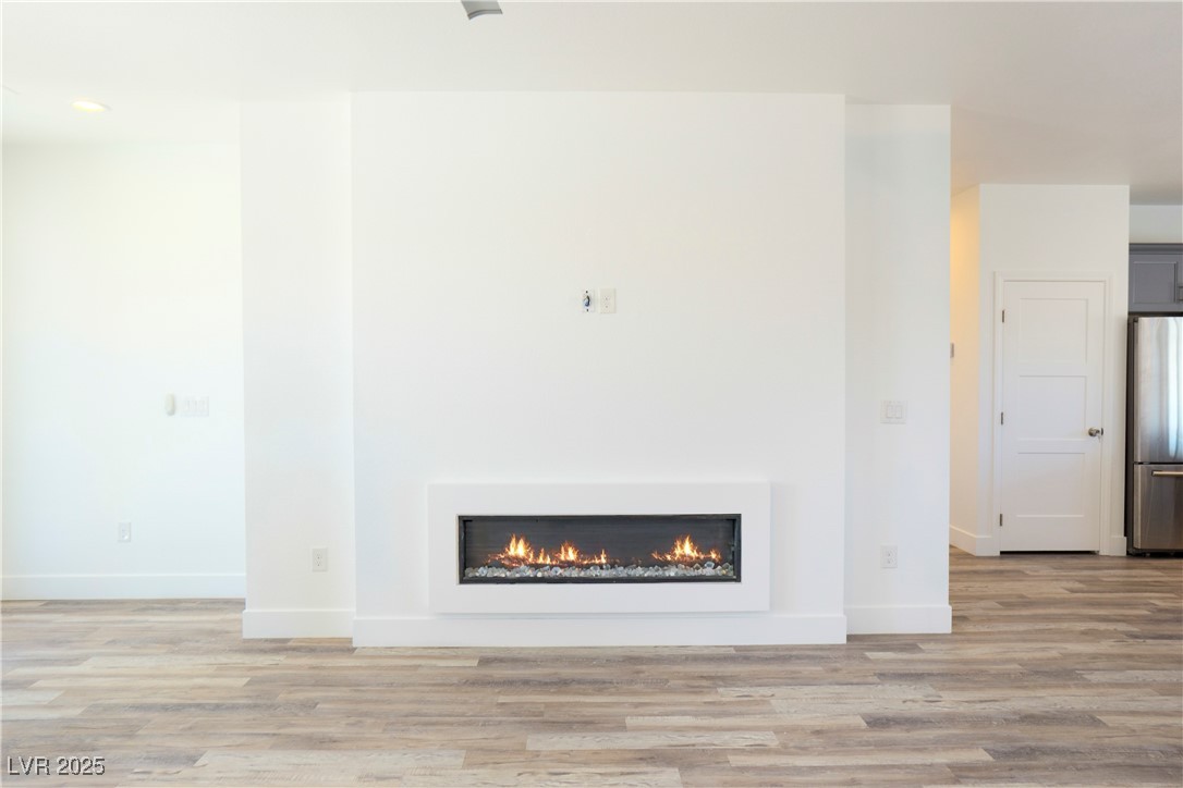 5400 Grain Mill Road Pahrump, NV 89061 - Photo 10 of 67 Unfurnished living room with light wood finished floors, baseboards, and a lit fireplace