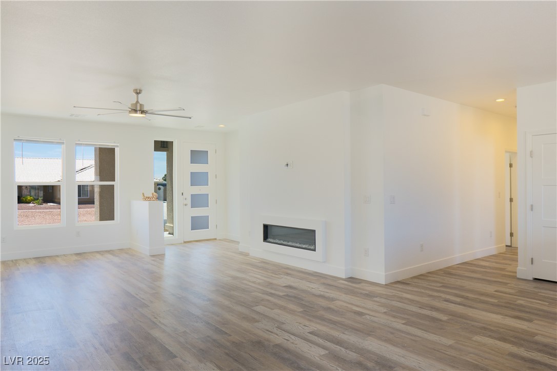 5400 Grain Mill Road Pahrump, NV 89061 - Photo 11 of 67 Unfurnished living room with wood finished floors, ceiling fan, baseboards, recessed lighting, and a glass covered fireplace