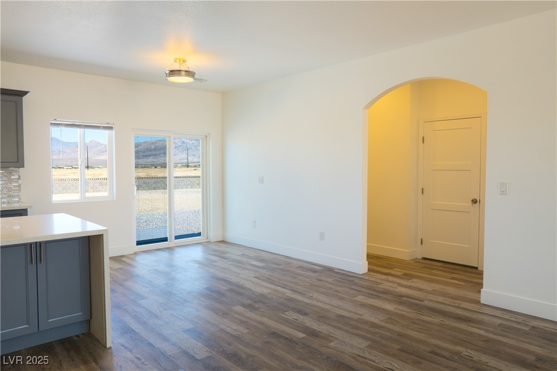 5400 Grain Mill Road Pahrump, NV 89061 - Photo 13 of 67 Unfurnished dining area with arched walkways, dark wood-style flooring, and baseboards