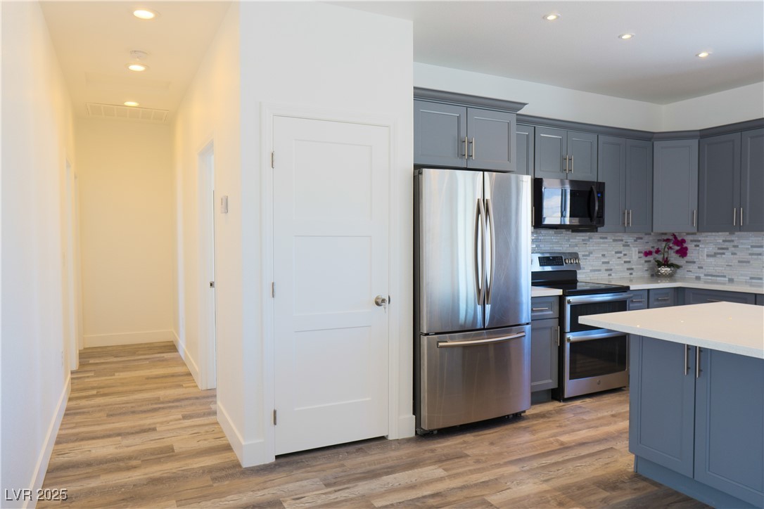 5400 Grain Mill Road Pahrump, NV 89061 - Photo 16 of 67 Kitchen with appliances with stainless steel finishes, light wood-type flooring, decorative backsplash, light countertops, and recessed lighting