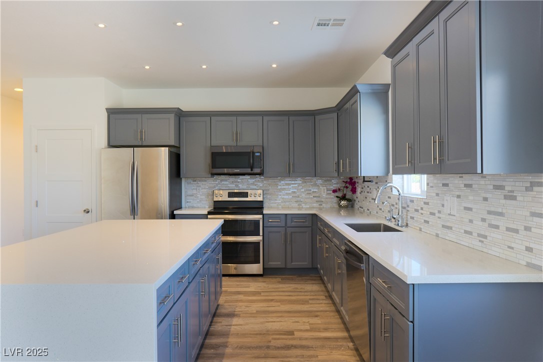 5400 Grain Mill Road Pahrump, NV 89061 - Photo 17 of 67 Kitchen featuring appliances with stainless steel finishes, a sink, wood finished floors, backsplash, and recessed lighting