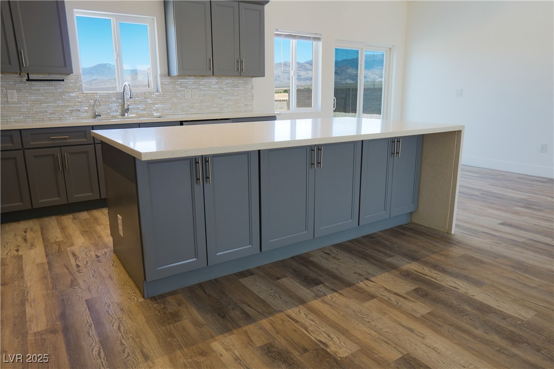 5400 Grain Mill Road Pahrump, NV 89061 - Photo 18 of 67 Kitchen with gray cabinets, a sink, dark wood-style floors, light countertops, and backsplash