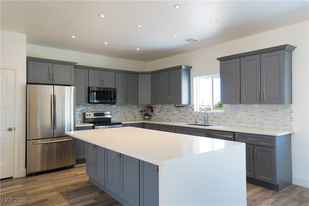 5400 Grain Mill Road Pahrump, NV 89061 - Photo 3 of 67 Kitchen with stainless steel appliances, a sink, a center island, gray cabinetry, and decorative backsplash