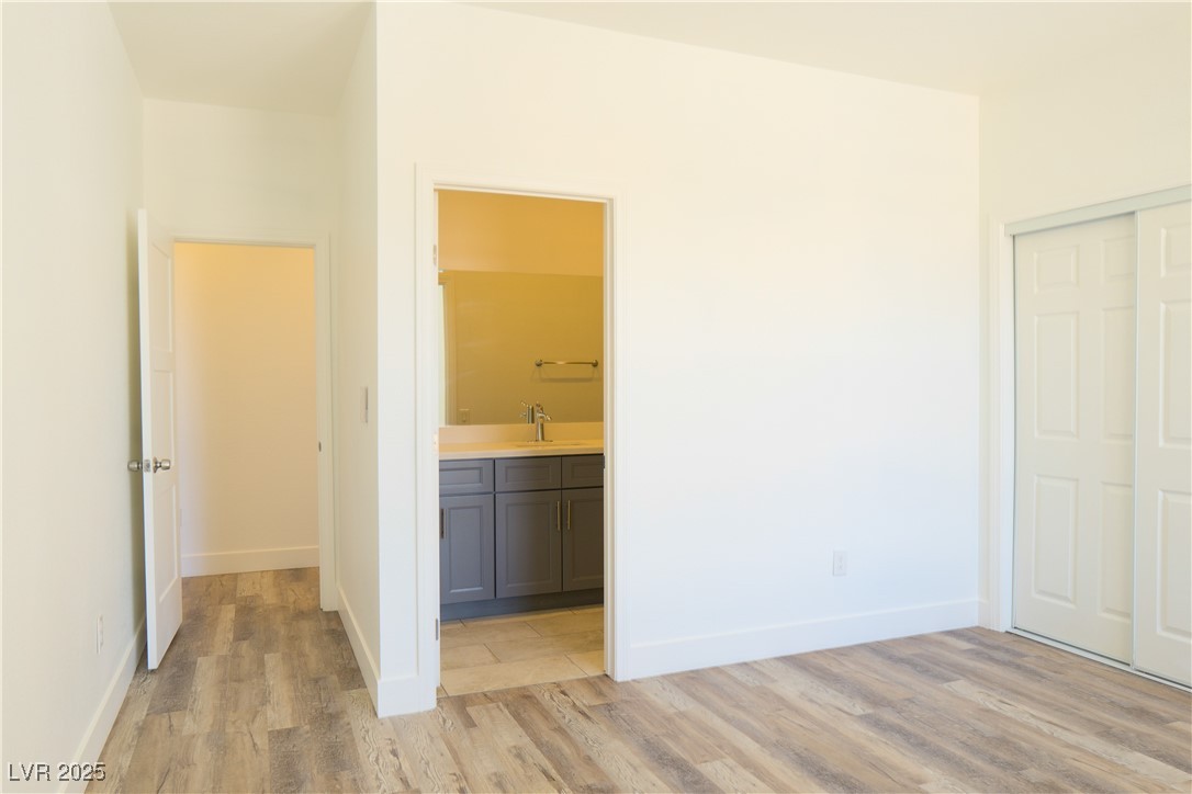 5400 Grain Mill Road Pahrump, NV 89061 - Photo 48 of 67 Unfurnished bedroom with light wood-style flooring, a sink, baseboards, a closet, and ensuite bath