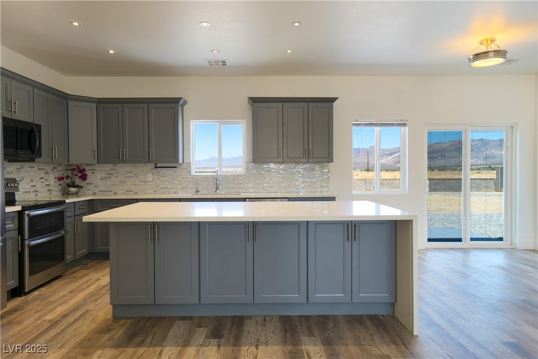 5400 Grain Mill Road Pahrump, NV 89061 - Photo 5 of 67 Kitchen featuring range with two ovens, black microwave, gray cabinetry, a sink, and a kitchen island