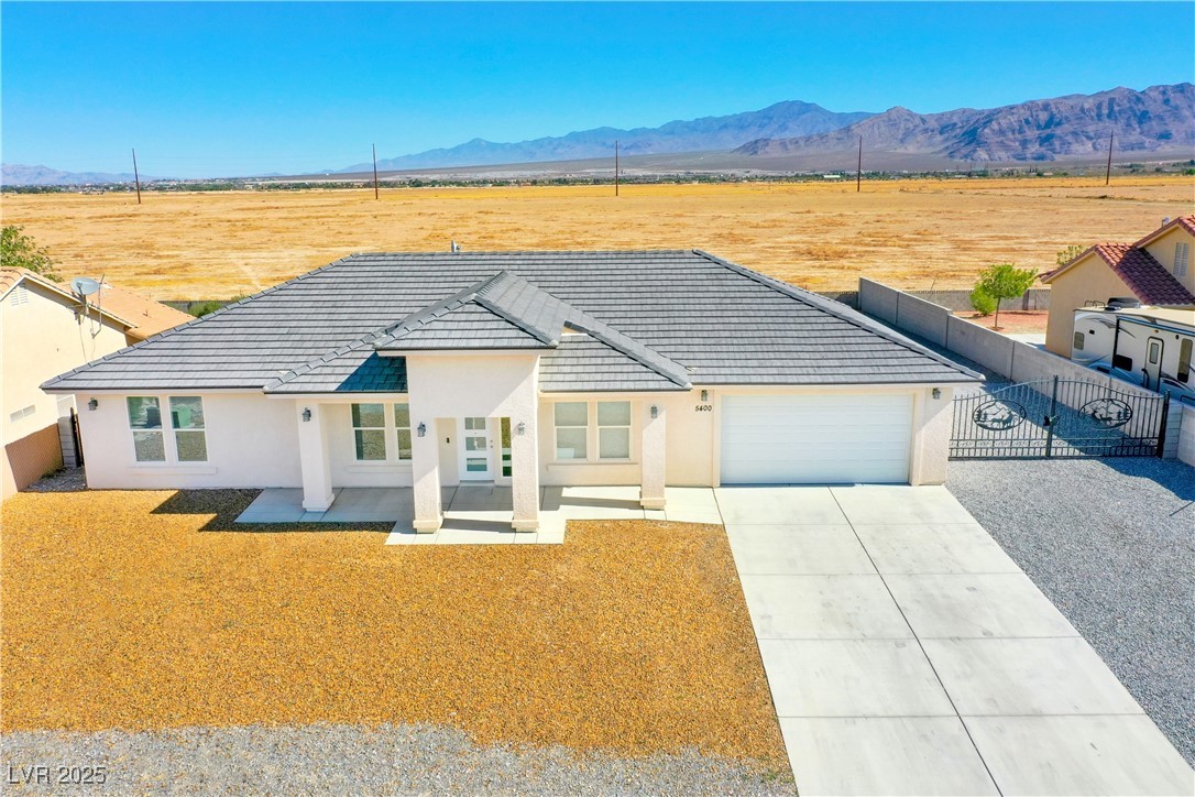 5400 Grain Mill Road Pahrump, NV 89061 - Photo 55 of 67 View of front of house with fence, a garage, a mountain view, and stucco siding