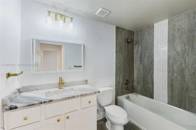 a bathroom with a granite countertop sink a toilet and shower