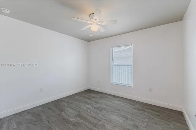 an empty room with wooden floor and fan