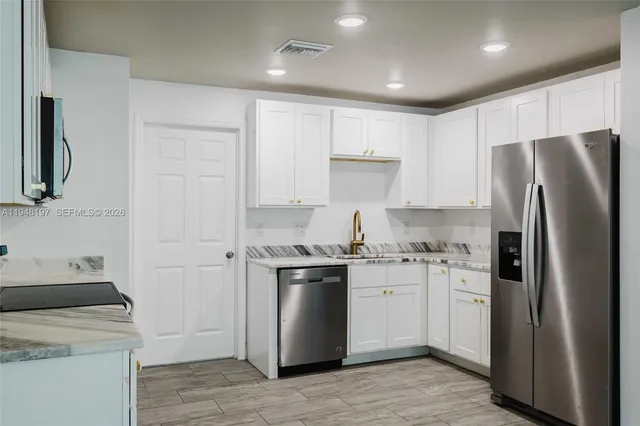 a kitchen with stainless steel appliances granite countertop a refrigerator a stove a sink and a microwave