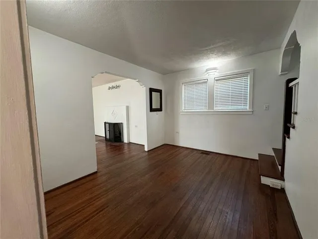 an empty room with wooden floor and fireplace