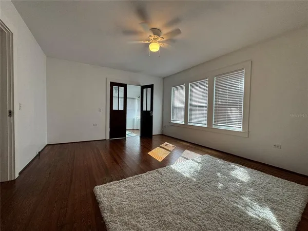 a view of an empty room with window and wooden floor