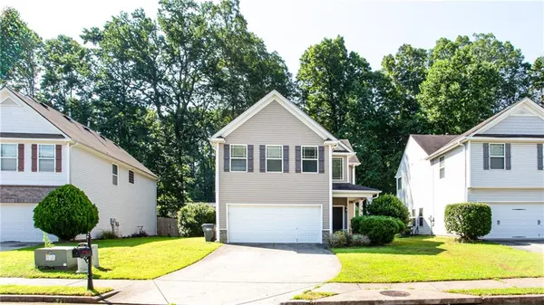 a view of a white house with a yard potted plants and a large tree