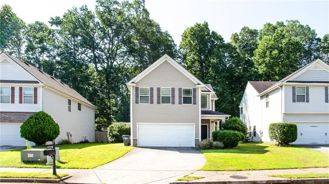 a view of a white house with a yard potted plants and a large tree