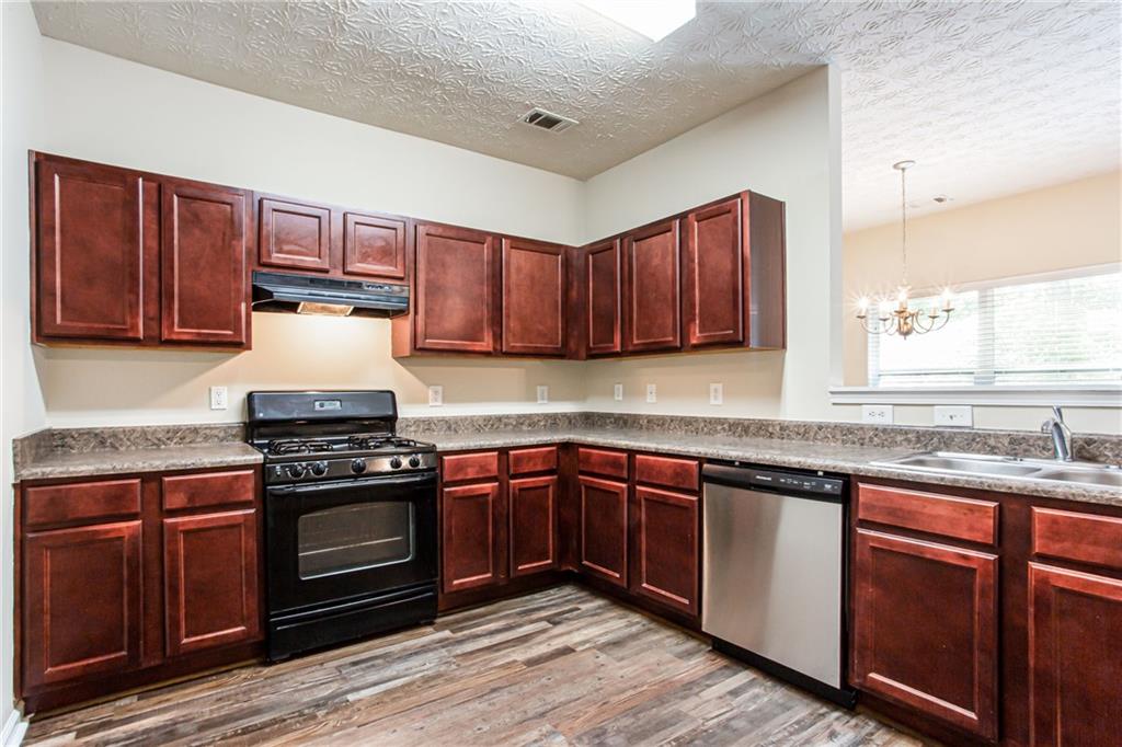 4628 McEver View Drive Sugar Hill, GA 30518 - Photo 11 of 30 a kitchen with stainless steel appliances granite countertop wooden cabinets stove top oven and sink