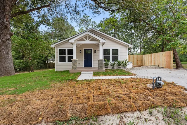 a front view of house with yard and trees in the background
