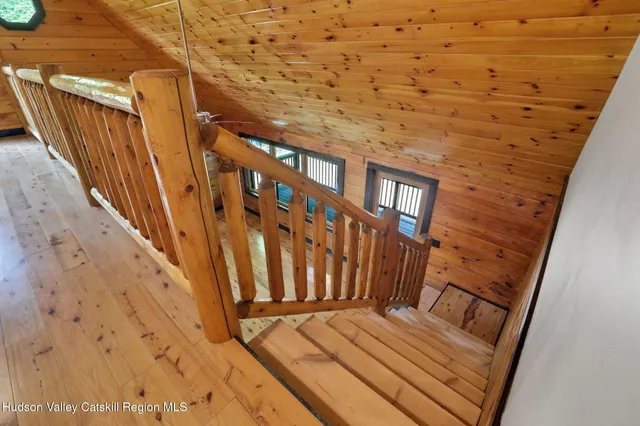 a view of wooden staircase with railing and white walls