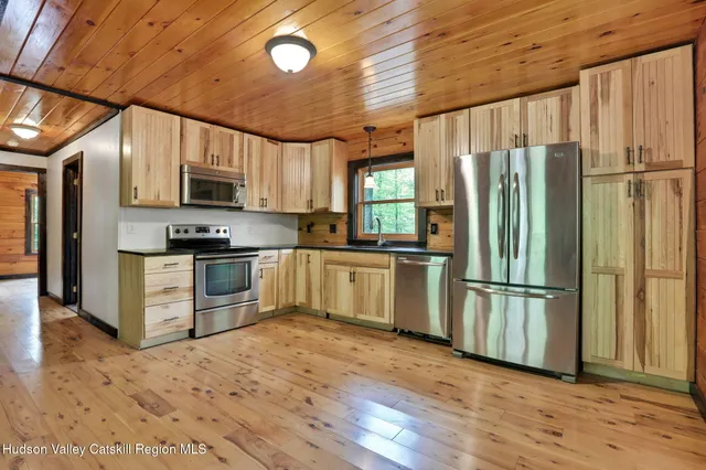 a kitchen with kitchen island granite countertop a refrigerator oven a sink and dishwasher with wooden floor