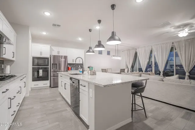 a kitchen with stainless steel appliances kitchen island granite countertop a sink and a refrigerator