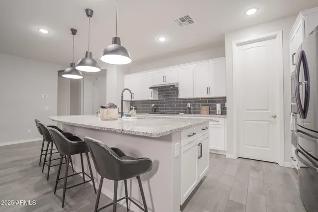 a kitchen with stainless steel appliances granite countertop a sink a stove a refrigerator and island with wooden floor