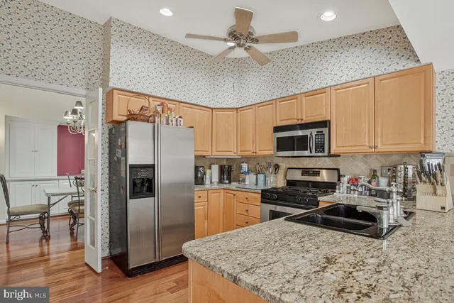 a kitchen with stainless steel appliances granite countertop a refrigerator a stove a microwave oven with white cabinets and wooden floor