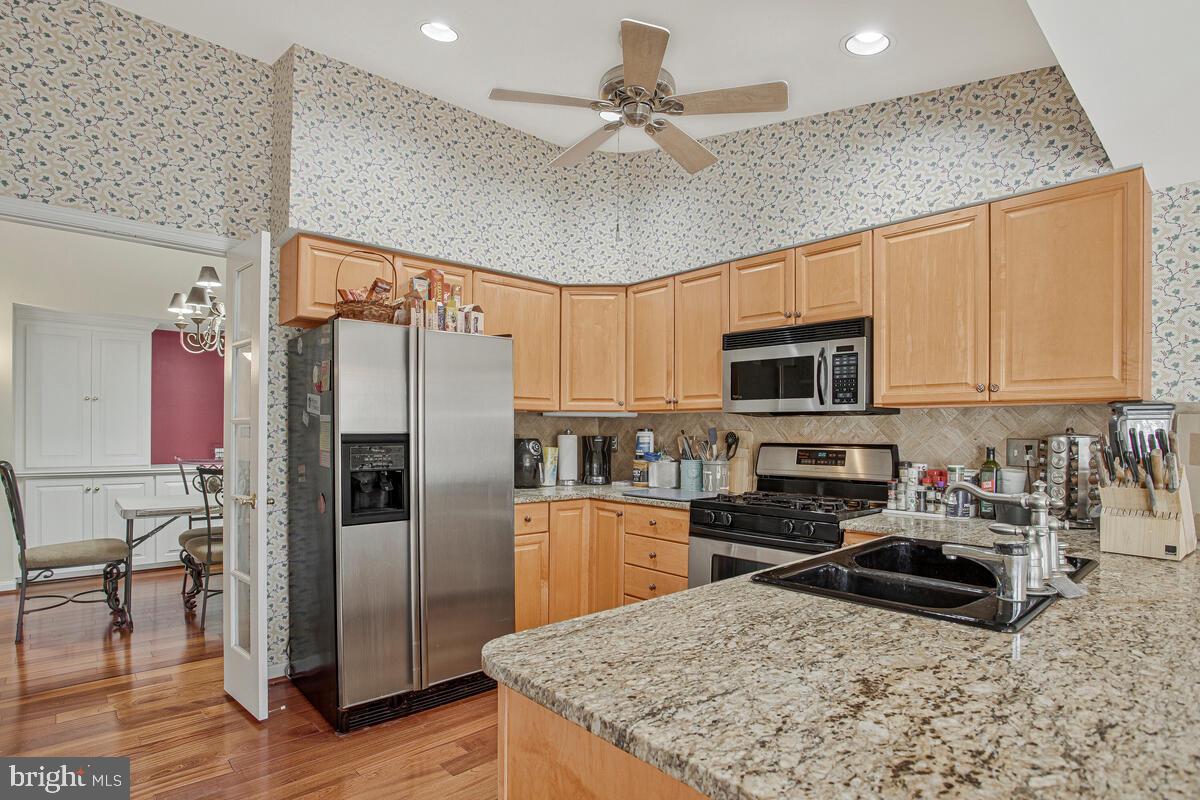 12300 Rosslare Ridge Road, Unit 508 Lutherville-Timonium, MD 21093 - Photo 19 of 40 a kitchen with stainless steel appliances granite countertop a refrigerator a stove a microwave oven with white cabinets and wooden floor