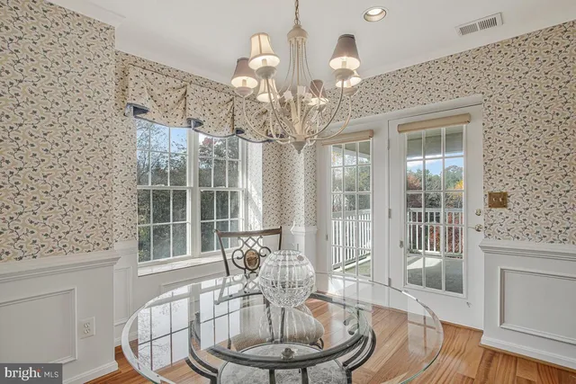 a dining room with wooden floor a chandelier a wooden table and chairs