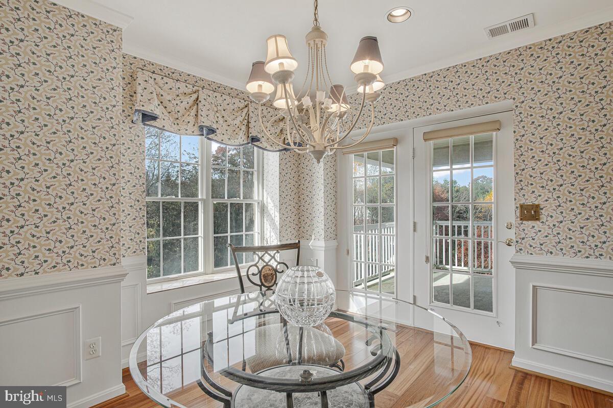 12300 Rosslare Ridge Road, Unit 508 Lutherville-Timonium, MD 21093 - Photo 22 of 40 a dining room with wooden floor a chandelier a wooden table and chairs
