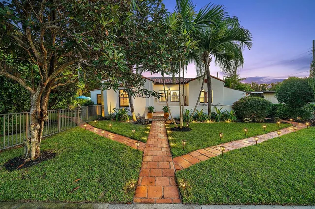 a front view of a house with a yard and large tree