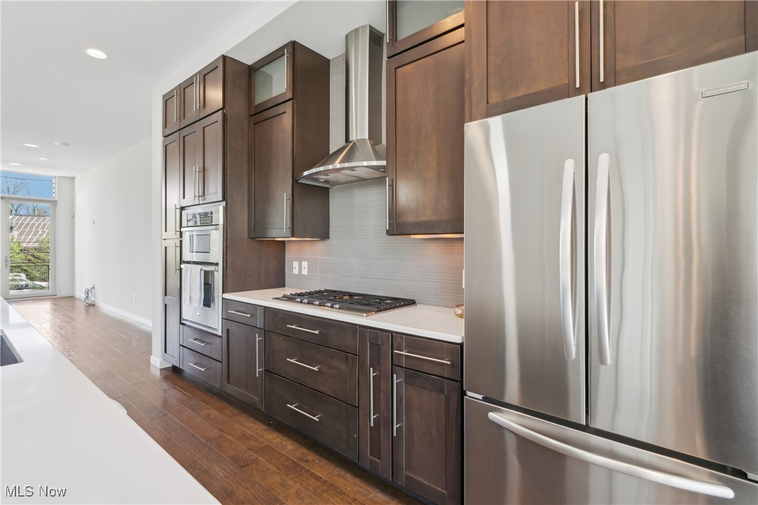 1852 Coltman Road Cleveland, OH 44106 - Photo 13 of 39 Kitchen featuring stainless steel appliances, dark wood finished floors, backsplash, wall chimney range hood, and light countertops