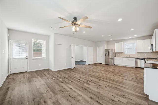 a view of an empty room with window and wooden floor