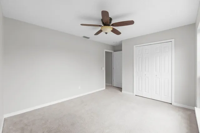 a view of an empty room and chandelier fan