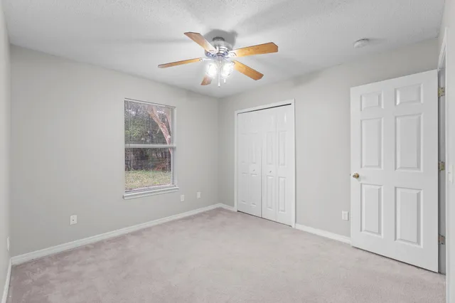 an empty room with fan and windows