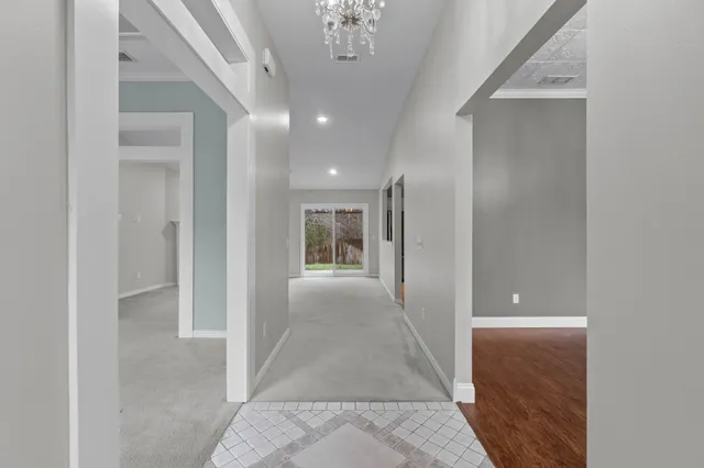 a view of a hallway with wooden floor and a bathroom