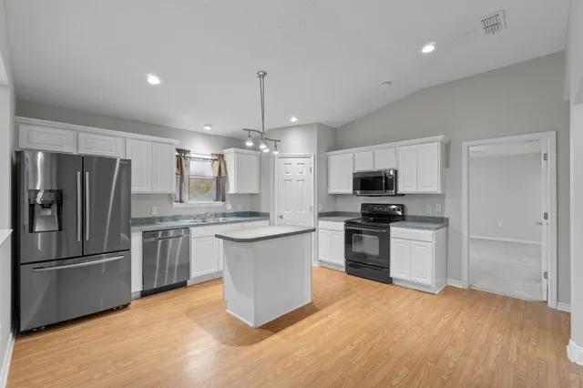 a kitchen with stainless steel appliances granite countertop a refrigerator a stove a sink and a microwave