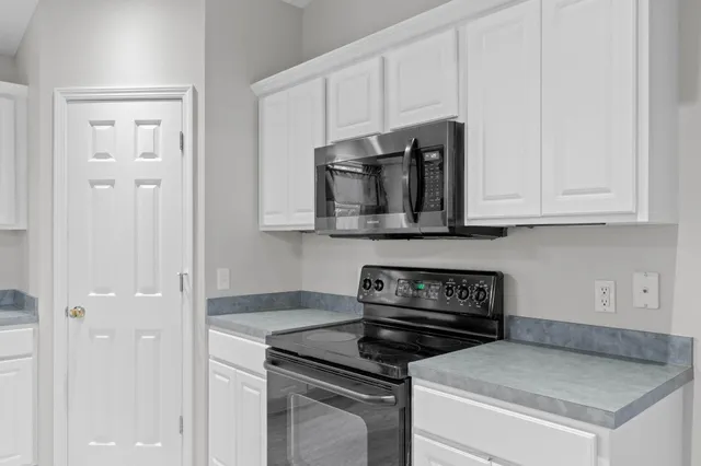 a kitchen with white cabinets and black appliances
