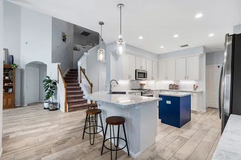 a kitchen with stainless steel appliances kitchen island granite countertop a table chairs in it and wooden floors